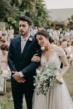 a bride and groom walking down the aisle at their outdoor wedding ceremony in front of an audience