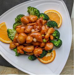 chicken and broccoli on a white plate with orange slices