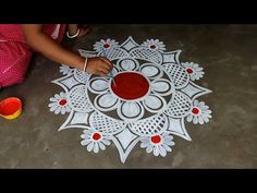 a child is making a paper doily with red and white flowers on it,