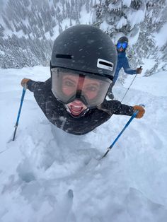 two people are skiing in the snow with skis and poles on their feet, one is sticking out his tongue