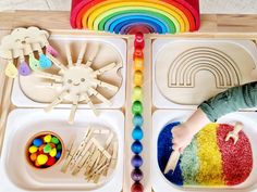 a child is playing with toys in a tray on the floor, including rainbows and building blocks