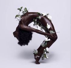 a naked woman with flowers on her head and hands behind her back, bending over to the side