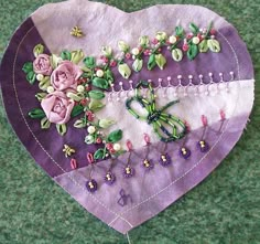 a purple heart with flowers and pins on it