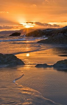 the sun is setting over some rocks on the beach with a poem written in it