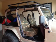 the interior of a jeep with its doors open and camo seat covers folded down