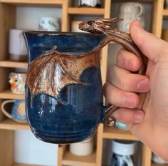 a hand holding a blue mug with a dragon on it