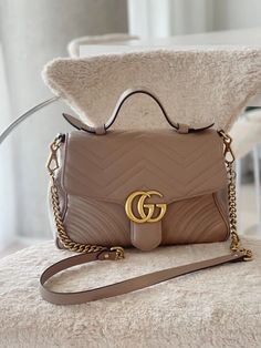 GG Marmont Top Handle Bag by Gucci. This quilted leather top handle bag features a carry handle at top and a detachable curb chain shoulder strap with lanyard clasp fastening and tonal leather strap pad. Logo hardware at face. Quilted heart graphic at back face. Foldover flap with press-release fastening. Leather logo flag and zippered pocket at interior. Microsuede lining in pink. Antiqued gold-tone hardware. Excellent condition. Estimated Retail: CAD $3,500 Condition: Preowned-Excellent All images are images of actual bag for sale. 100% Authentic Heart Graphic, Gg Marmont, Leather Logo, Quilted Leather, Press Release, Curb Chain, Handle Bag, Leather Top, Antique Gold