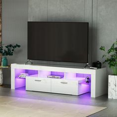 a white entertainment center with purple lights on the side and a large television mounted to it's wall