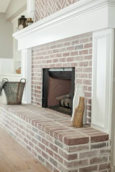 a brick fireplace in a living room with white trim and wood flooring on the mantle