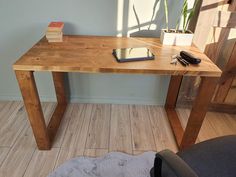 a wooden table with a cell phone on it and a plant in the corner next to it