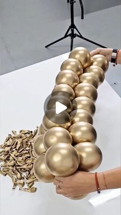 a person is placing gold balls in the shape of a caterpillar on a table