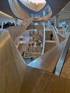 people are walking up and down the stairs in a building with wooden railings on both sides