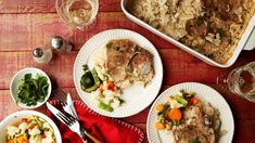 three plates with meat, vegetables and rice are on the table next to wine glasses