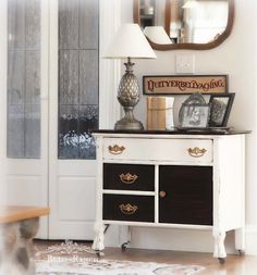 a white and black dresser sitting in front of a mirror