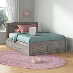 a bed sitting on top of a wooden floor next to a pink and blue rug