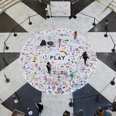 an overhead view of people standing around a play sign in the middle of a tiled floor