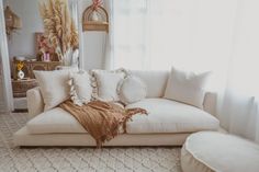 a living room with a white couch and pillows