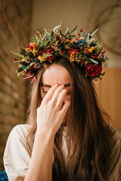 a woman with long hair wearing a flower crown on her head and covering her eyes