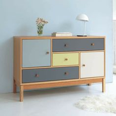 a multicolored chest of drawers with a lamp on top and a white rug