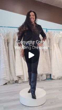 a woman standing on top of a white pedestal in front of wedding dresses and gowns