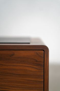 an electronic device is sitting on top of a wooden table with white walls behind it