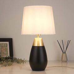 a black and gold lamp sitting on top of a table next to a framed photo