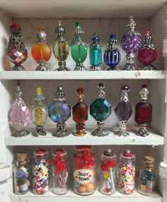 a shelf filled with lots of different types of perfume bottles and candy in glass jars