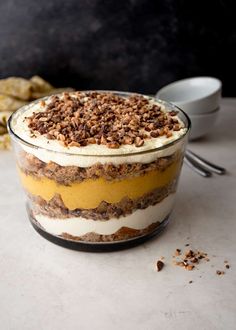 an image of a dessert in a glass bowl on a table with crackers and spoons