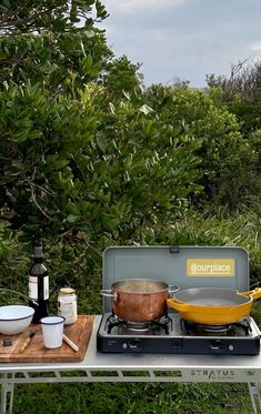 an outdoor table with pots and pans on it