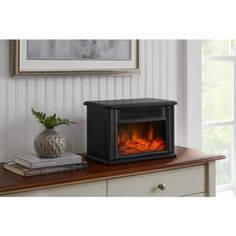 an electric fireplace in a living room with a potted plant on the end table