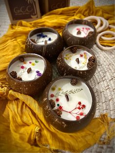 four coconuts with flowers on them are sitting on a yellow cloth next to some candles