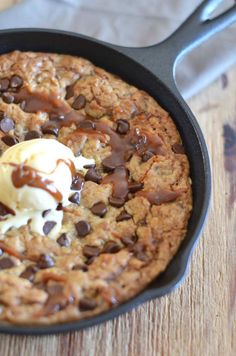 a chocolate chip cookie with ice cream in a cast iron skillet on a wooden table