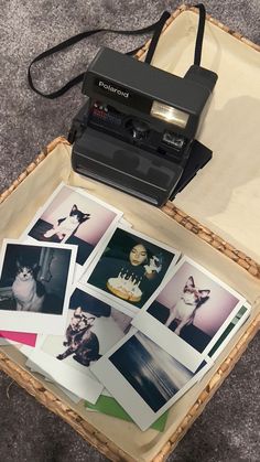 an old fashioned camera sitting on top of a table next to pictures in a suitcase