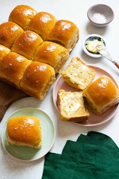 rolls and butter on a plate next to a cutting board with bread in the middle