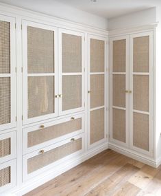 an empty room with white cabinets and wood floors