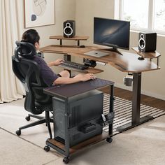 a person sitting at a computer desk in front of a monitor and keyboard with speakers