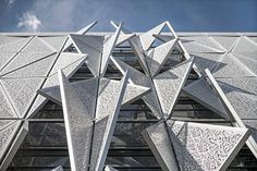 an architectural building with many triangular shapes on it's side, against a blue sky