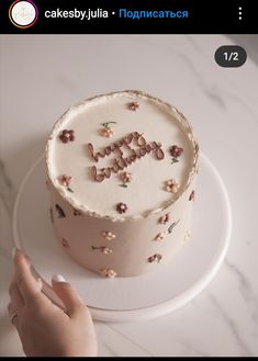 someone is holding their hand up to a cake with the word happy written on it