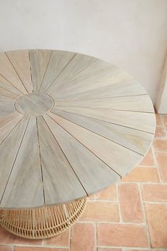 an umbrella shaped table sitting on top of a red brick floor next to a white wall