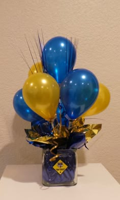 a vase filled with blue and yellow balloons