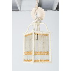 a white birdcage hanging from the ceiling with beaded trimming around it