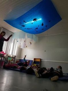 a group of people laying on the floor in a room with a blue skylight hanging from the ceiling