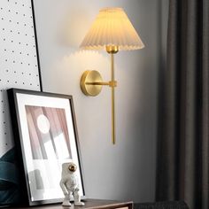 a lamp that is on the wall next to a table with a framed photo and an animal figurine