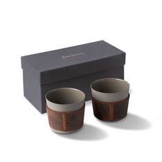 two brown and white cups sitting in front of a black box