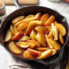 apples are being cooked in a skillet on the stove top with other cooking utensils