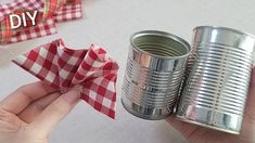 someone is holding a tin can with a red and white checkered napkin