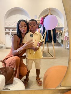 a woman taking a selfie with a child in front of a mirror at a store