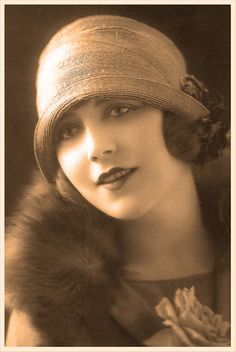 an old black and white photo of a woman wearing a hat with fur on it