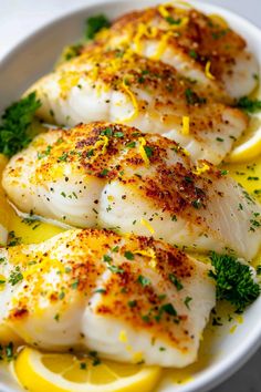 some fish with lemon slices and parsley in a white bowl on top of a table