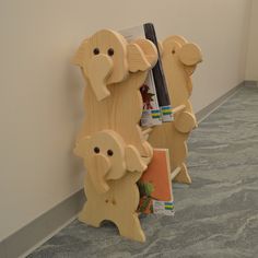 three wooden elephants standing next to each other in front of a book shelf with books on it